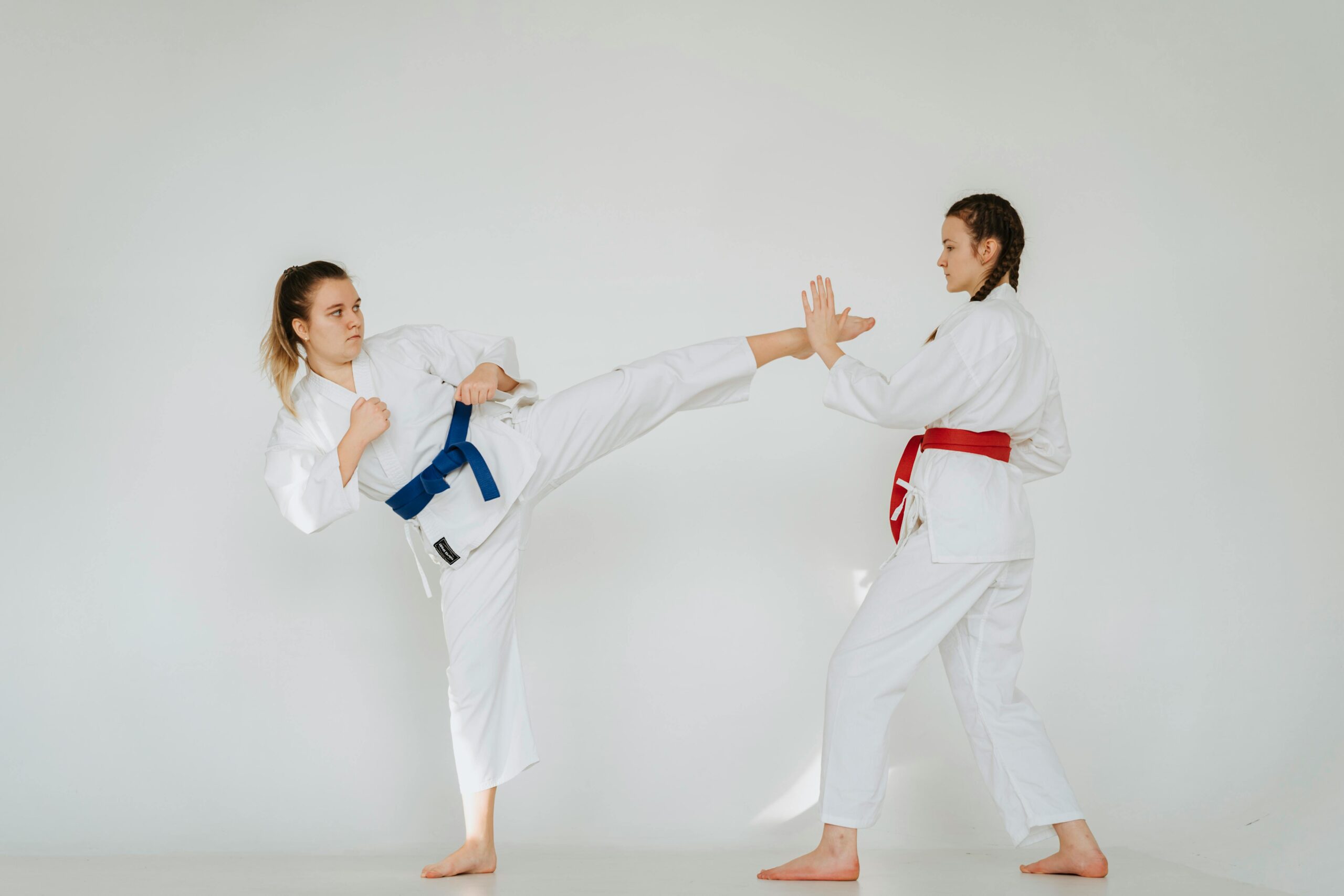 Dynamic shot of two women practicing martial arts techniques in a studio setting.