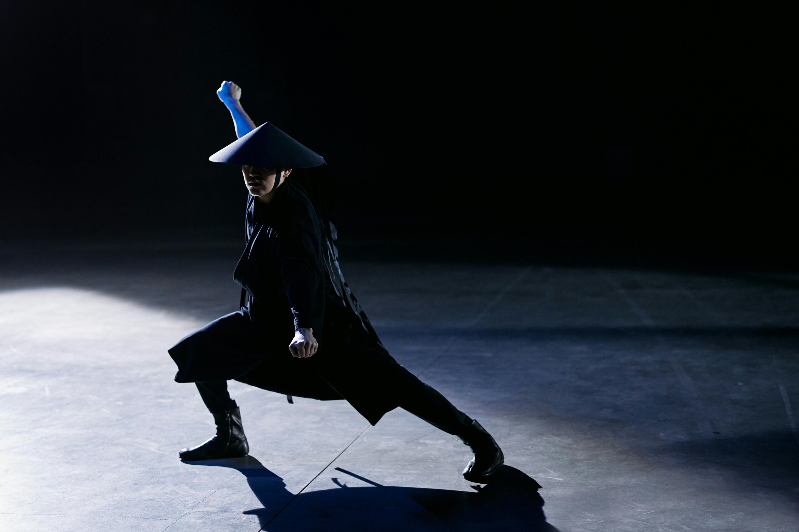 A skilled cosplayer strikes a dramatic pose as a game character in a dark studio setting.