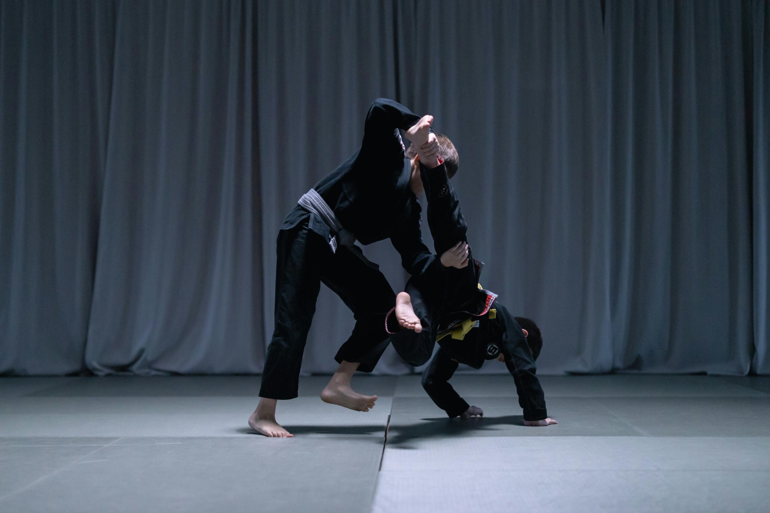 Two young athletes practicing Brazilian Jiu Jitsu with focus and skill indoors.