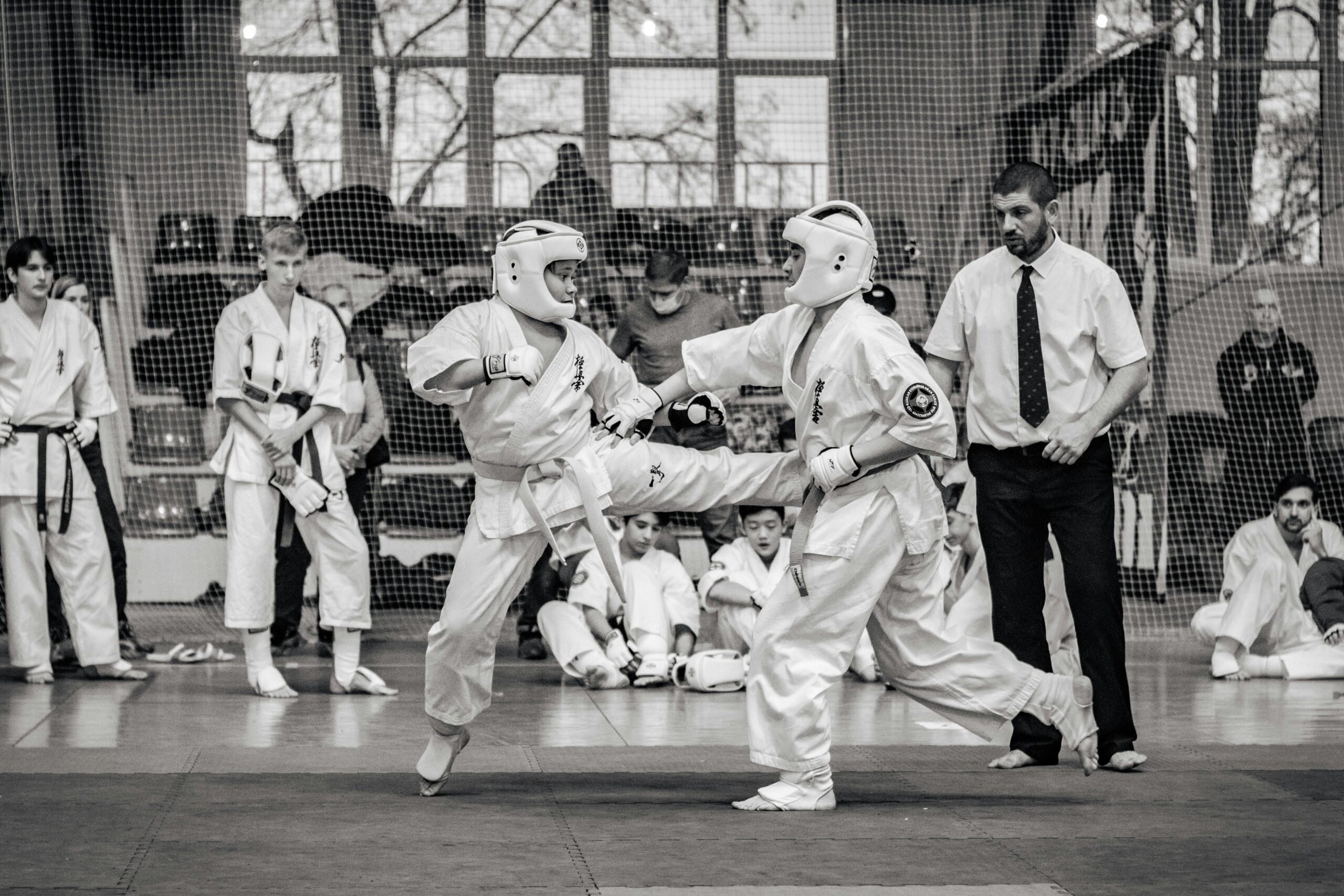Two martial artists compete in a thrilling karate match during a tournament, showcasing intense focus and skill.