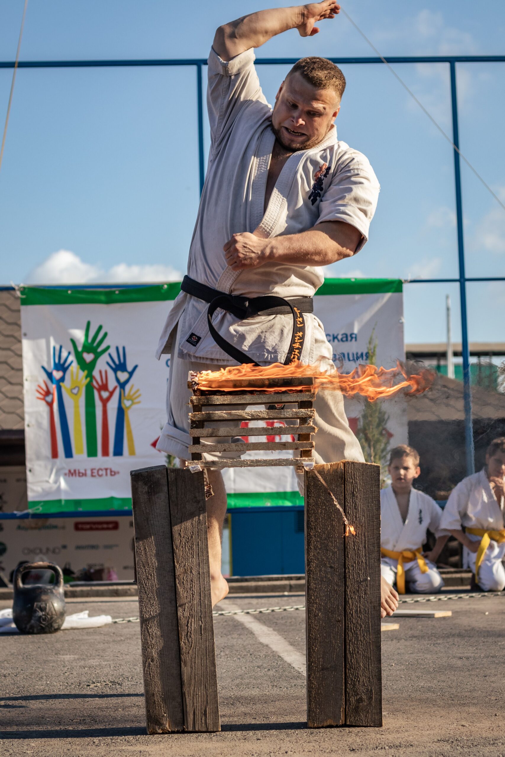 A martial artist performs a powerful brick breaking demonstration outdoors.
